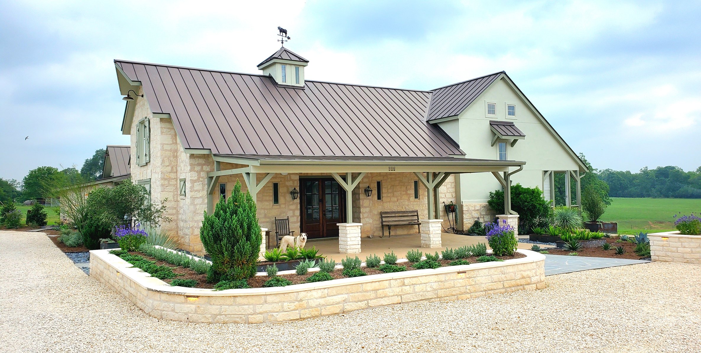 Curved limestone retaining wall and planting beds wrapping the front of the home
