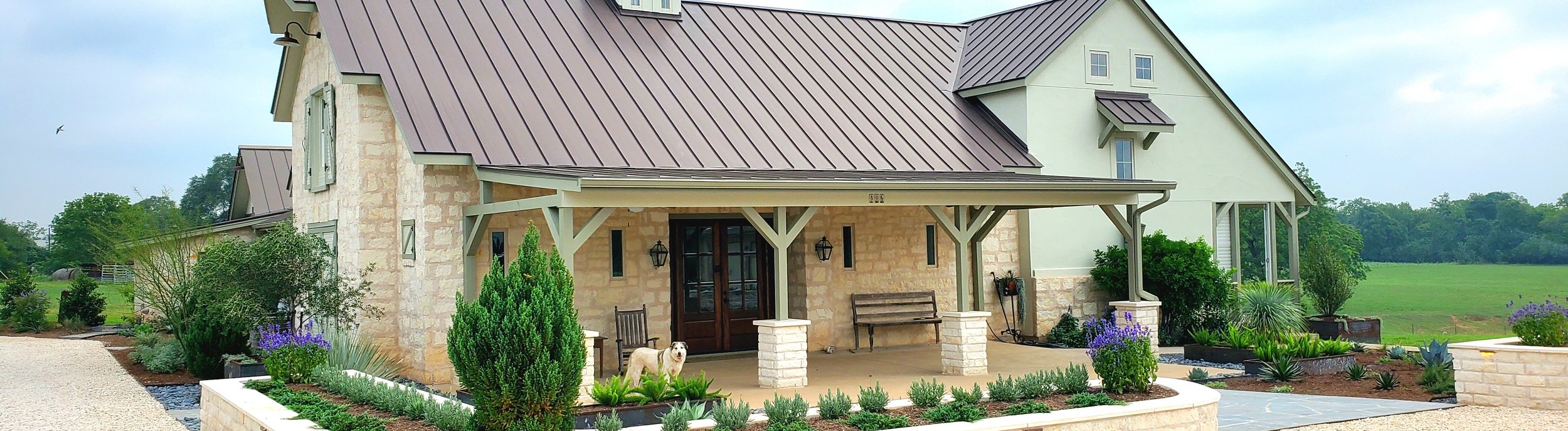 Smithville, TX ranch landscape with curved limestone retaining wall and native plantings by Thrive Landscape and Design