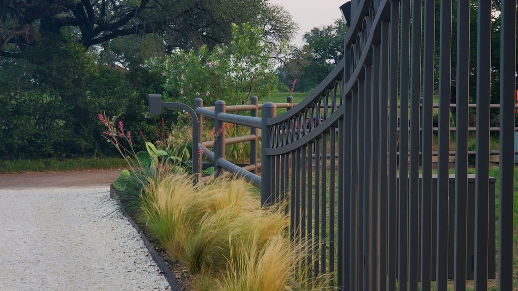 Iron gate and fence posts set along a gravel driveway during installation at a ranch property