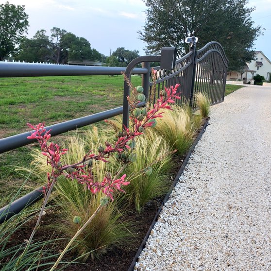 Iron driveway entry gate with an access-control post at a Smithville ranch