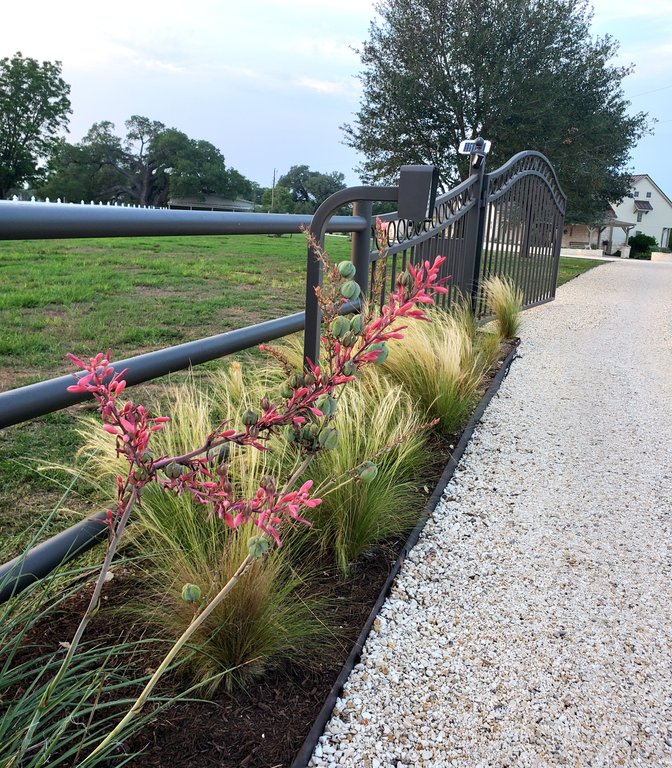 Iron entry gate with an access-control post along a gravel ranch driveway