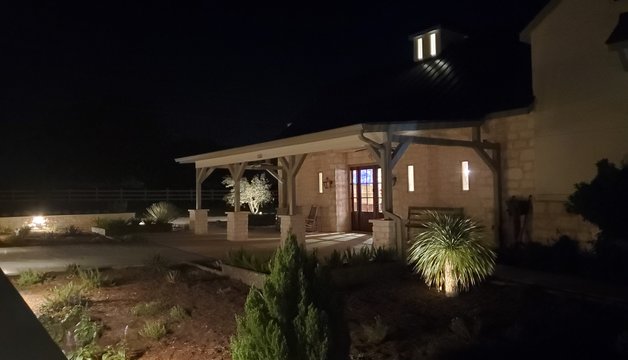 Accent lighting glowing on a stone pavilion and xeriscape at a Smithville ranch