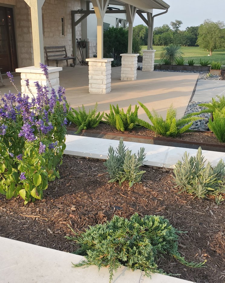 Mulched stone planter beds along a flagstone walkway at a Central Texas home