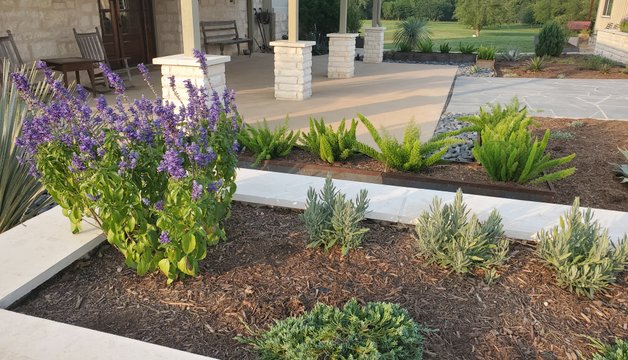 Flagstone walkway running past a stacked-stone planter bed at a Central Texas home
