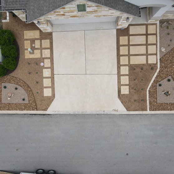 Aerial view of a graded Spicewood front yard with paver driveway and gravel beds in Austin
