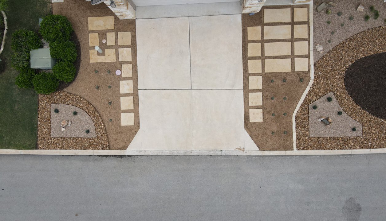 Aerial view of a paver driveway with gravel borders fronting a Spicewood xeriscape