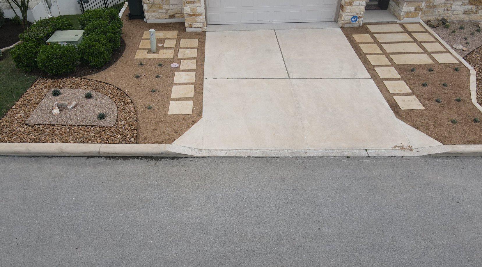 Cream pavers and ornamental grasses lining the driveway approach