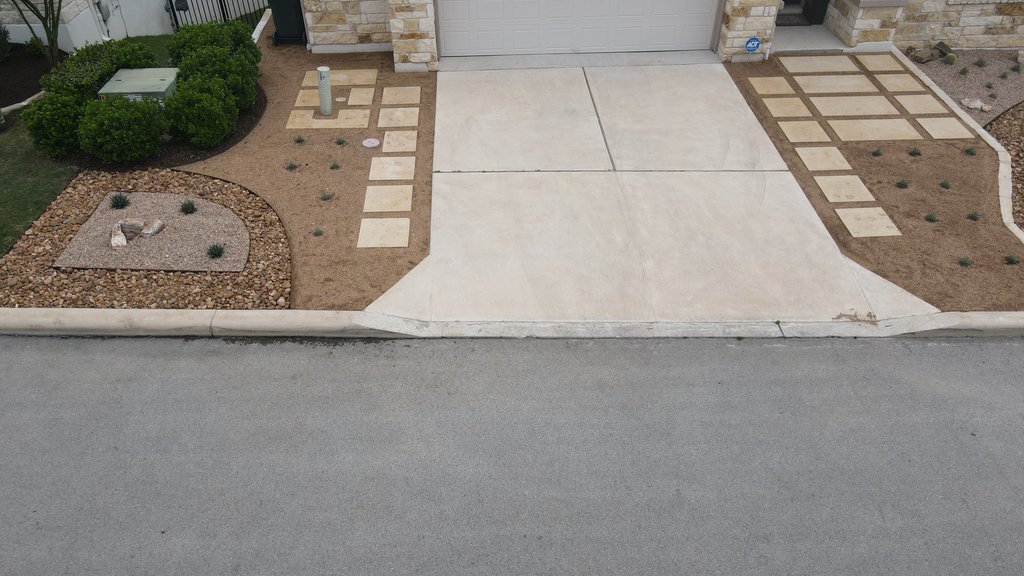 Finished graded Spicewood front yard with paver driveway, gravel, and ornamental grasses