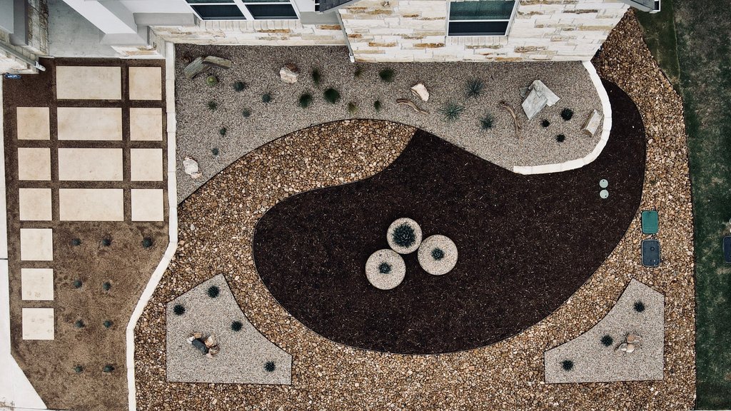Aerial view of limestone paver paths and gravel xeriscape framing a finished driveway in the Austin area