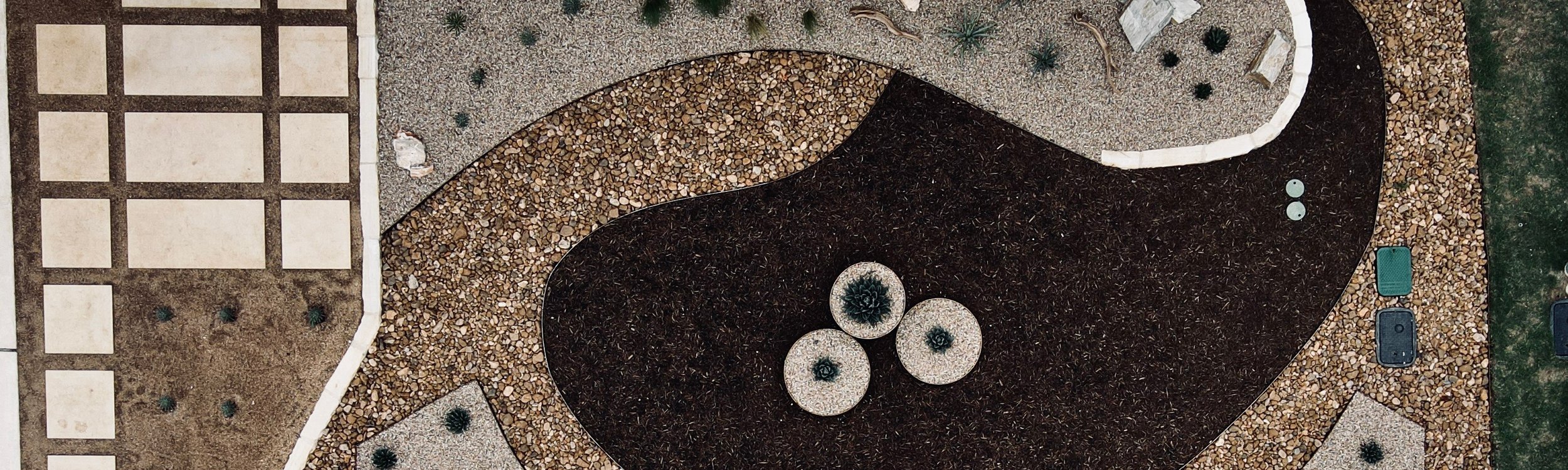 Aerial view of a freshly graded Spicewood front yard with gravel, mulch beds, and pavers in Austin