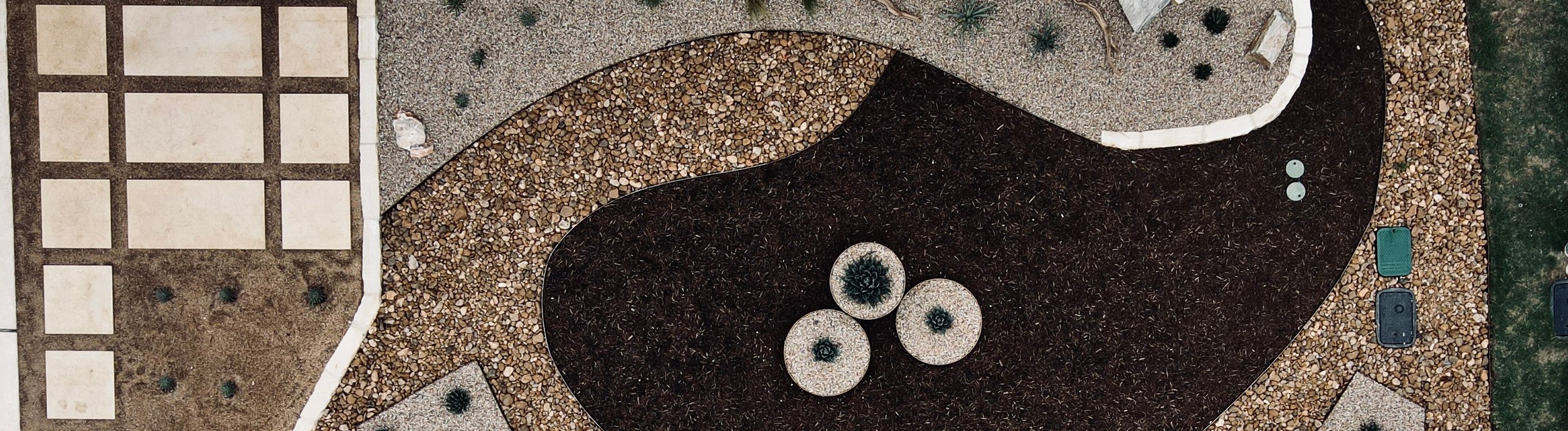 Aerial view of a water-wise front yard xeriscape in Spicewood, TX with cream pavers, gravel, and mulch beds