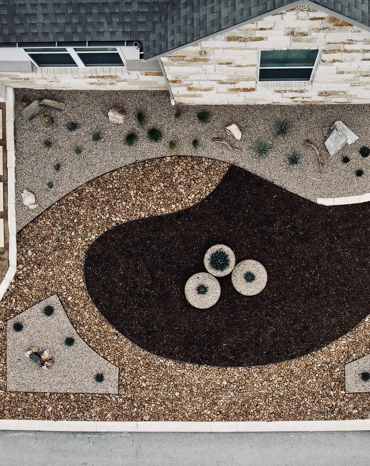 Aerial view of a front yard with limestone pavers, gravel, and a concrete driveway in the Austin area