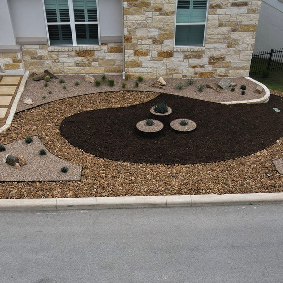 Gravel, mulch, and planters in a water-wise Spicewood front-yard xeriscape