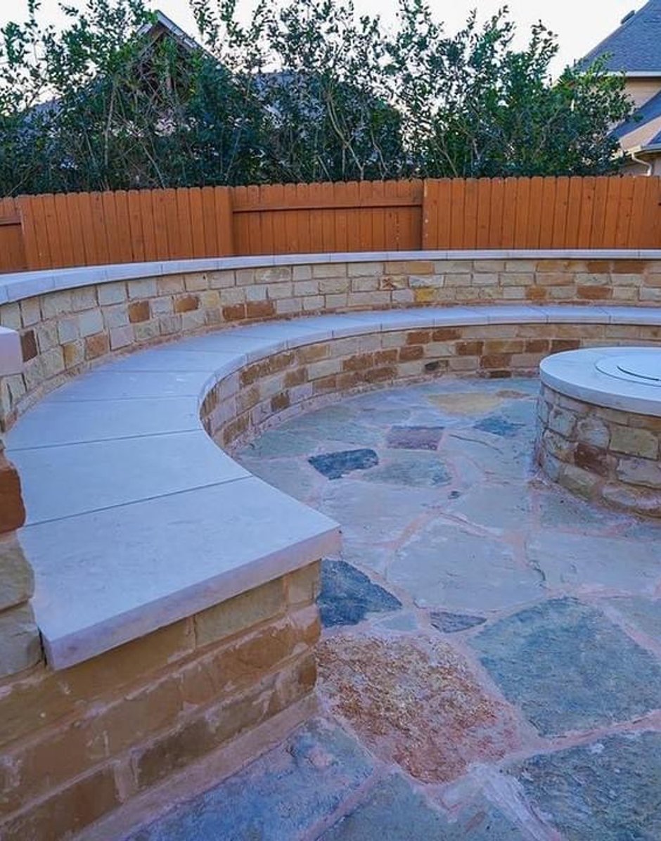 Built-in circular fire pit wrapped in a curved stacked stone seating wall