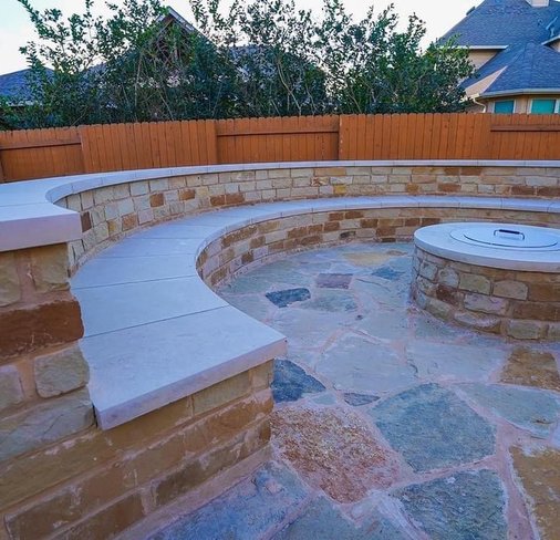 Custom deck area with a firepit, flagstone patio, and bench seating wall in Steiner Ranch