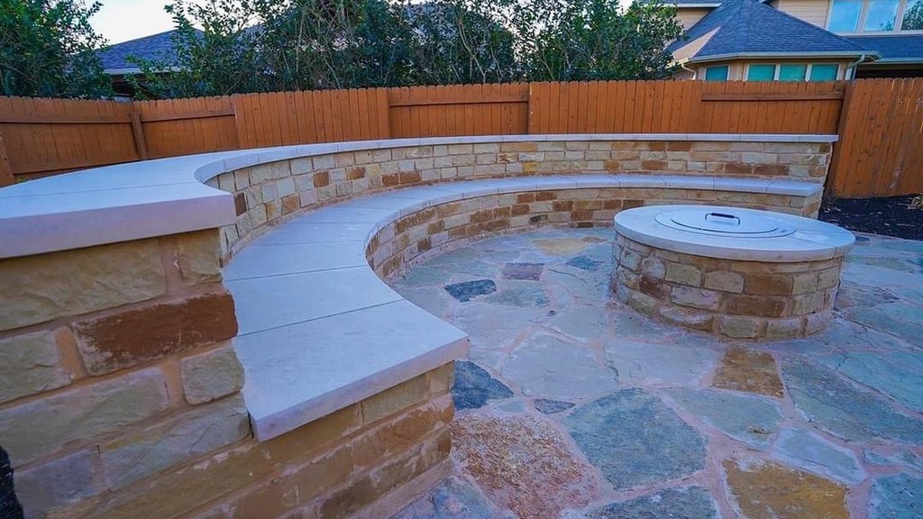 Finished stone fire pit ringed by a flagstone patio and curved bench seating wall in Steiner Ranch