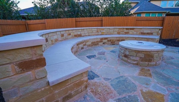 Stone fire pit with a flagstone patio and bench seating wall in Steiner Ranch