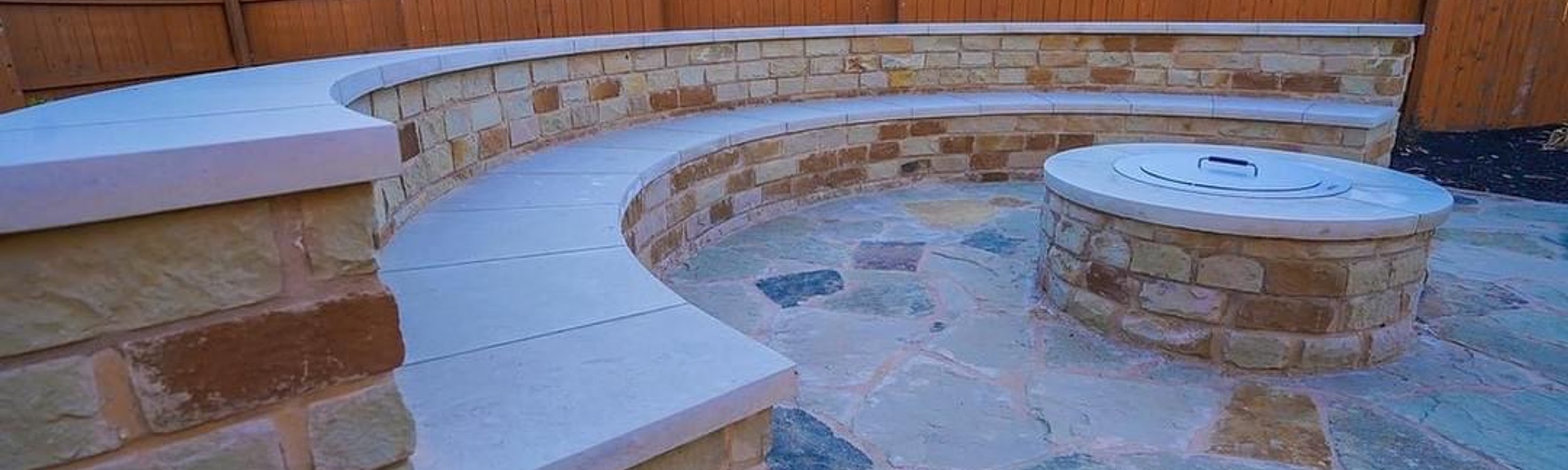 Custom flagstone patio with a fire pit and seating wall at a Steiner Ranch home in Austin