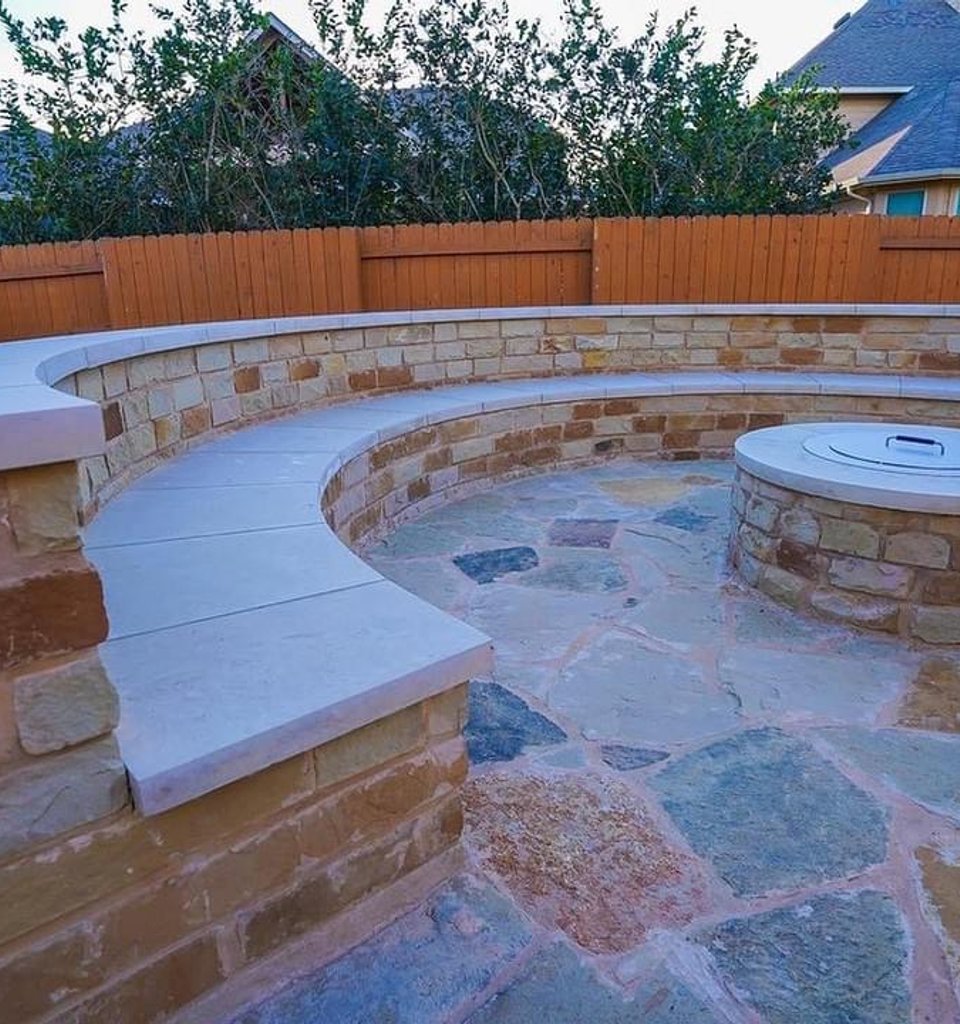 Steiner Ranch fire-pit patio framed by a stone bench seating wall