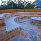 Built-in stone fire pit with a curved bench seating wall on a flagstone patio in a Steiner Ranch backyard near Austin
