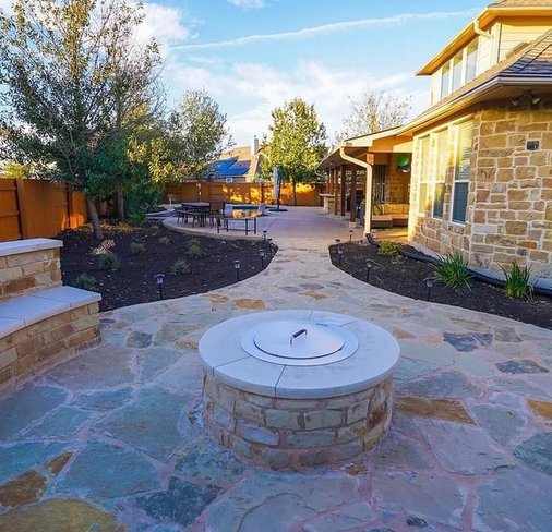 Backyard firepit and bench seating wall on a flagstone patio in Steiner Ranch