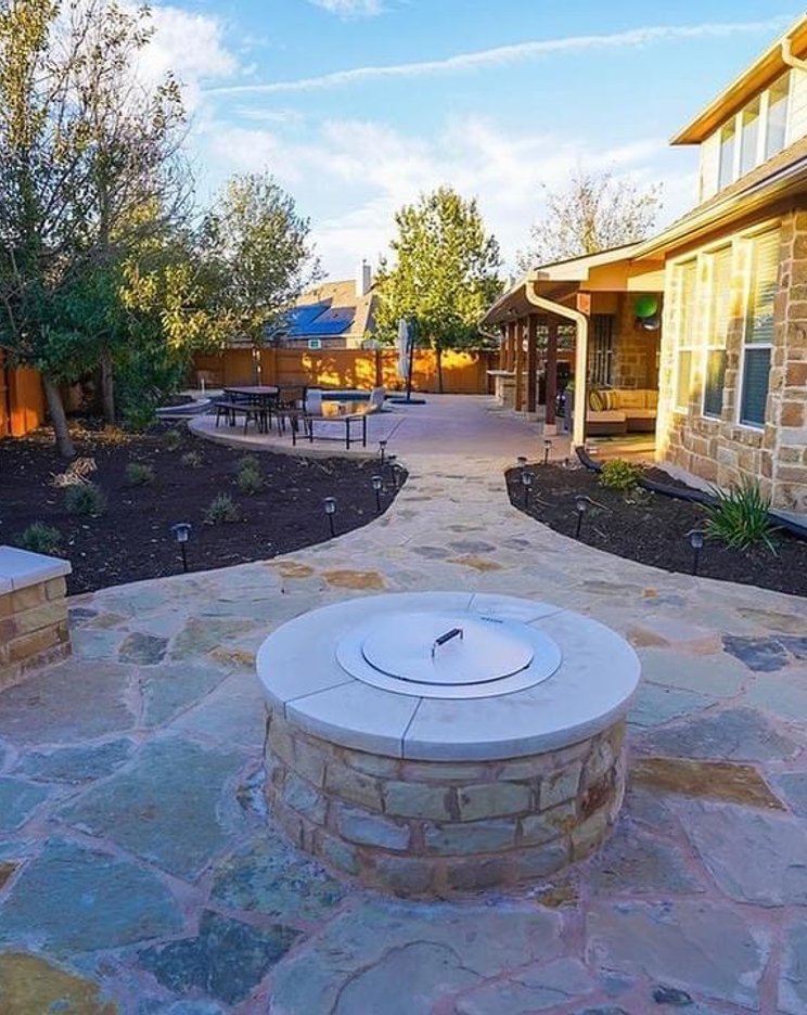 Stone fire pit with flagstone patio and curved bench seating wall at a Steiner Ranch home