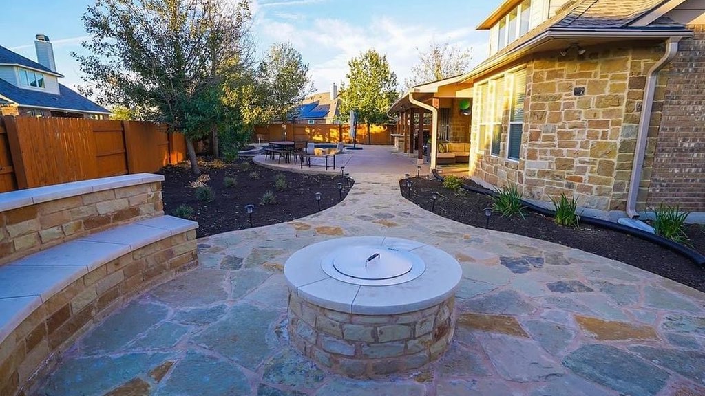 Finished flagstone patio with a fire pit, seating wall, and planting beds at a Steiner Ranch home