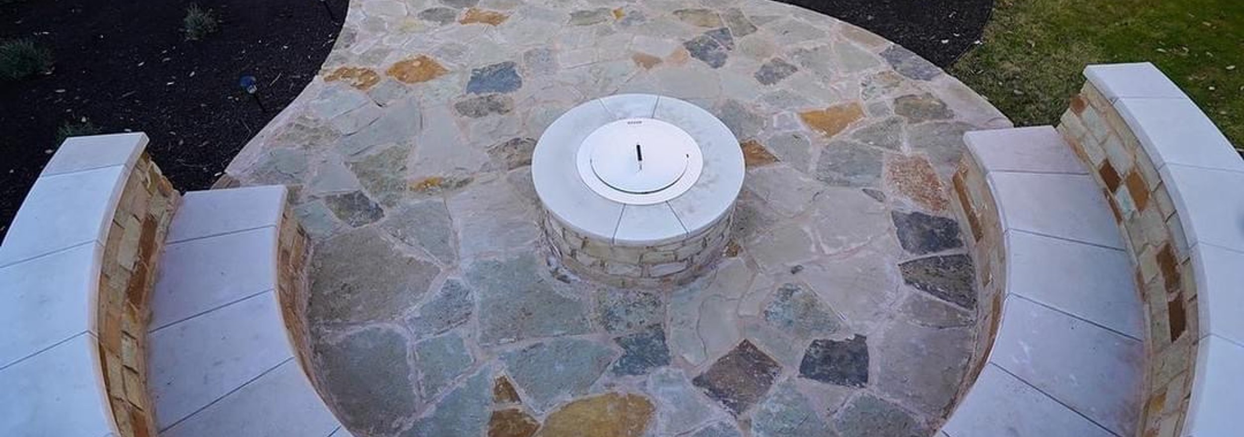 Golden flagstone patio with the fire pit, seating wall, and surrounding planting beds