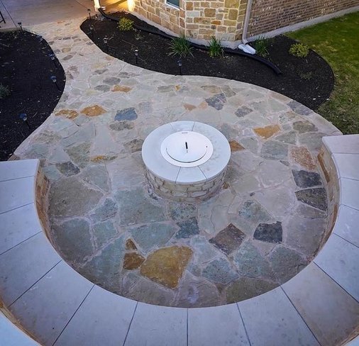 Flagstone fire-pit area with a bench seating wall and planting beds in Steiner Ranch