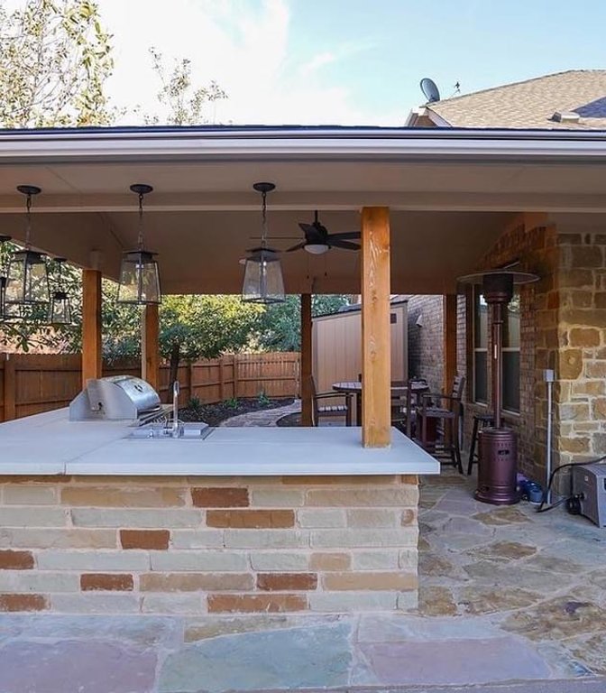 Shaded outdoor kitchen under a pergola on a flagstone patio at Steiner Ranch