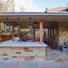 Outdoor kitchen under a pergola beside a pool and flagstone patio in Steiner Ranch