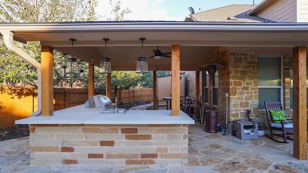 Flagstone patio being set beneath a pergola and outdoor kitchen at a Steiner Ranch home