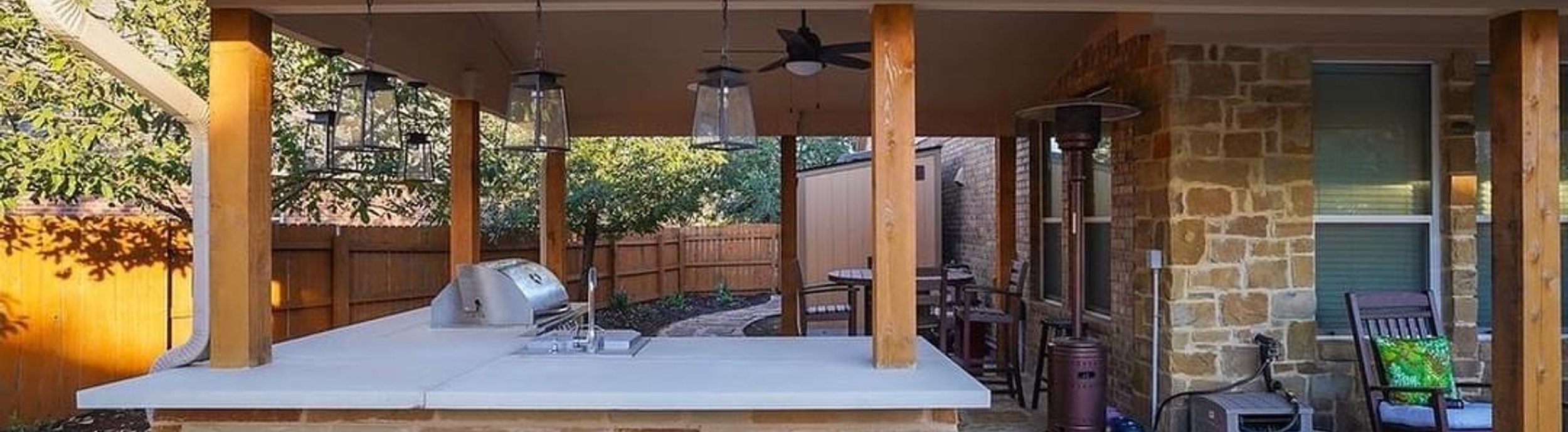 Outdoor kitchen under a pergola beside a pool and flagstone patio in Steiner Ranch