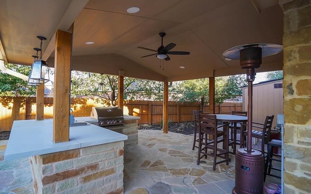 Built-in outdoor kitchen with a stainless grill under a cedar pergola next to a flagstone patio in Steiner Ranch near Austin