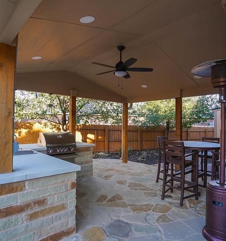 Steiner Ranch outdoor kitchen with a built-in grill under a pergola on a flagstone patio