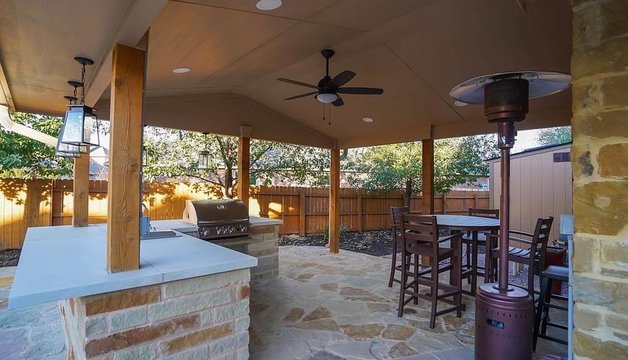 Covered outdoor kitchen with a grill and flagstone patio at a Steiner Ranch home