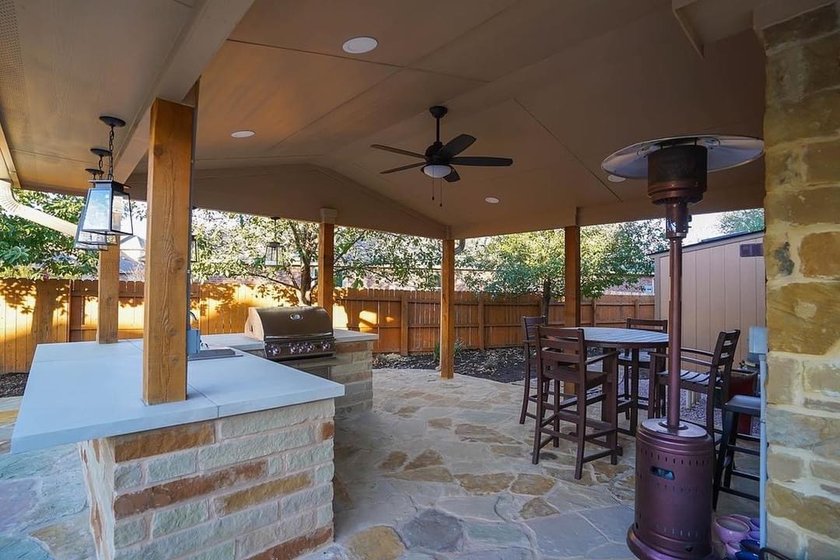 Built-in outdoor kitchen with a stainless grill under a cedar pergola next to a flagstone patio in Steiner Ranch near Austin