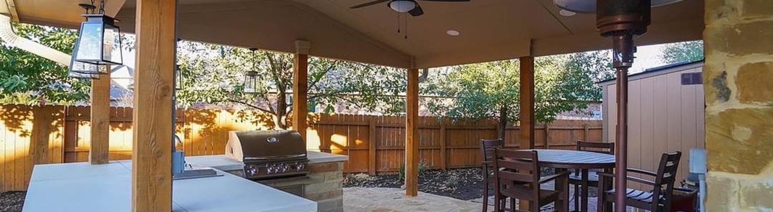 Built-in outdoor kitchen with a stainless grill under a cedar pergola next to a flagstone patio in Steiner Ranch near Austin