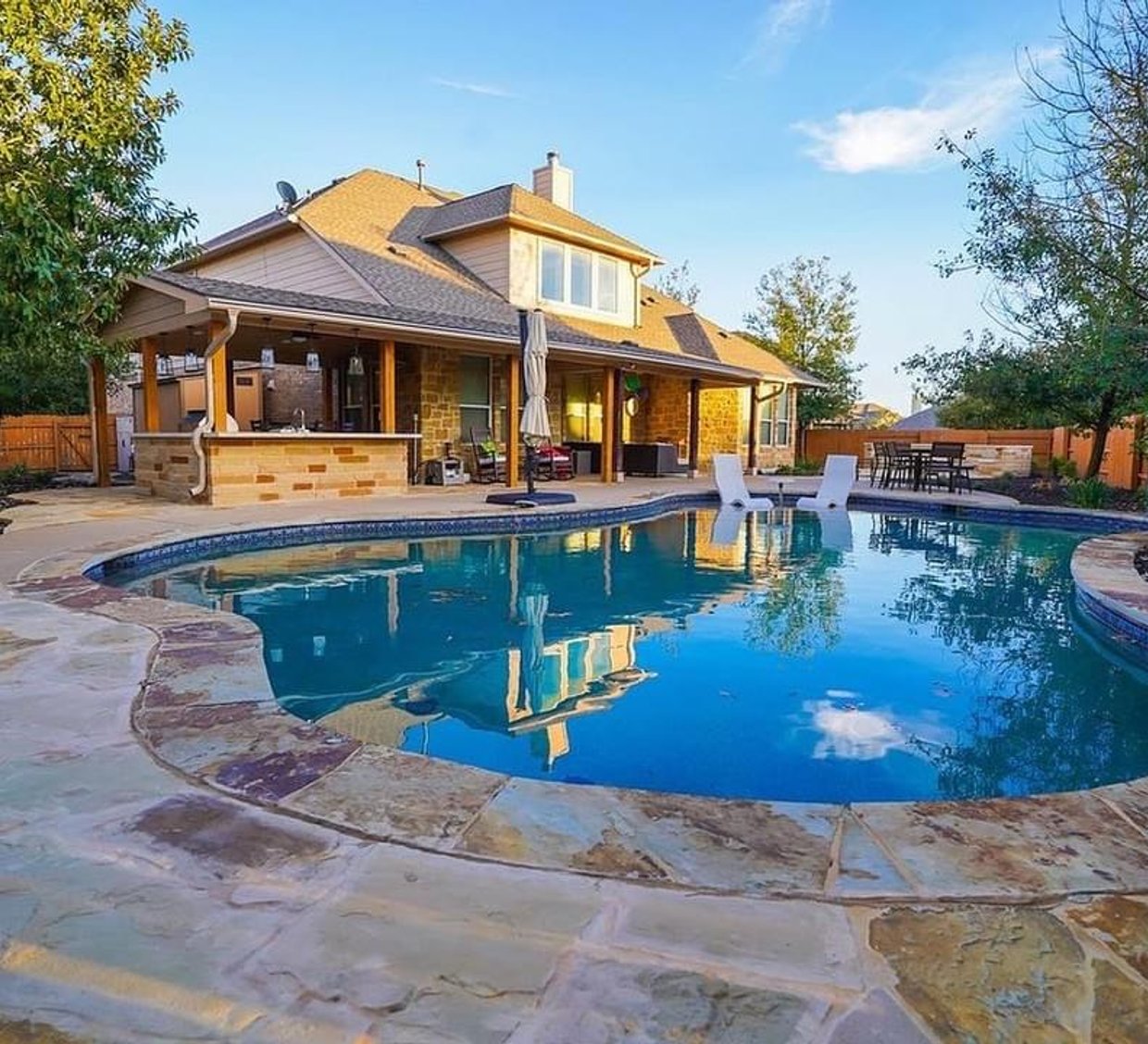 Steiner Ranch backyard with a pool, flagstone patio, pergola, and outdoor kitchen