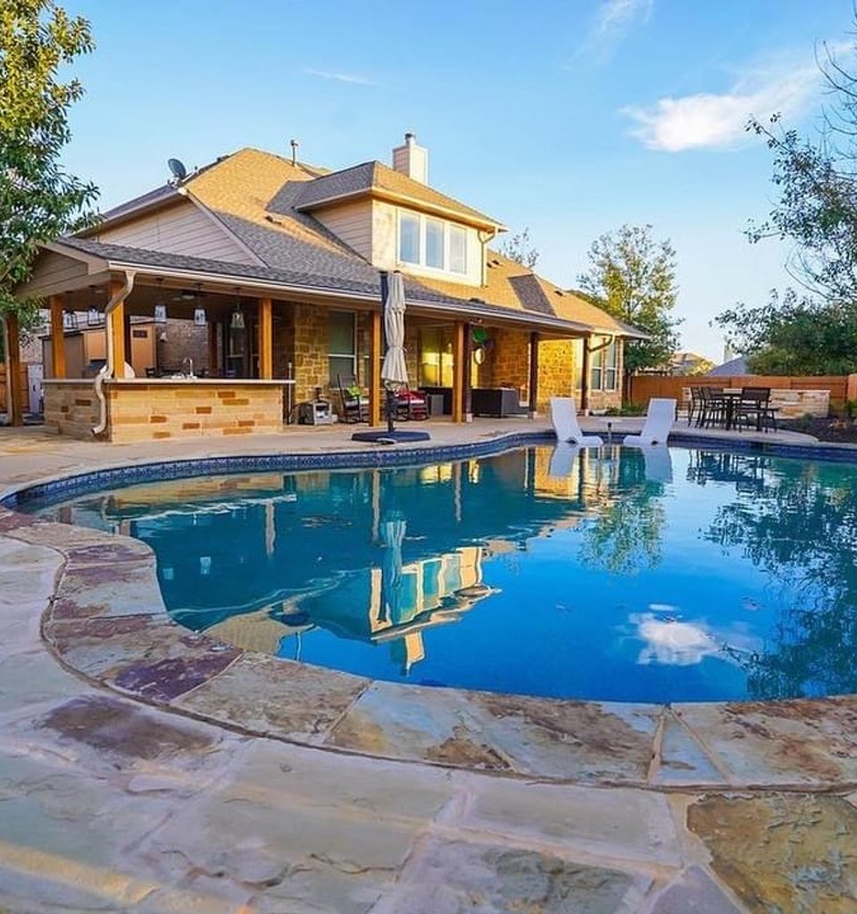 Steiner Ranch backyard with a pool, flagstone patio, pergola, and outdoor kitchen