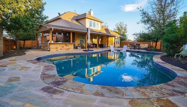 Steiner Ranch outdoor living space with a pool, flagstone patio, pergola, and outdoor kitchen