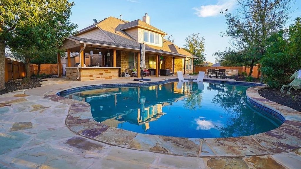 Finished pergola over an outdoor kitchen beside the pool and flagstone patio in Steiner Ranch