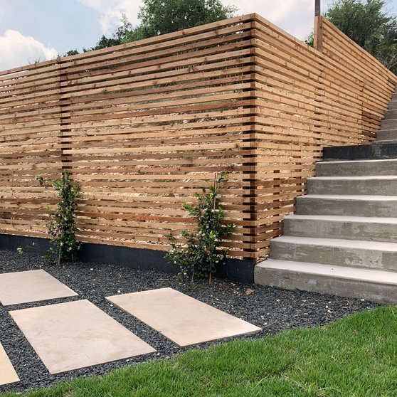 Tall cedar slat privacy fence wrapping a custom Westlake Hills home