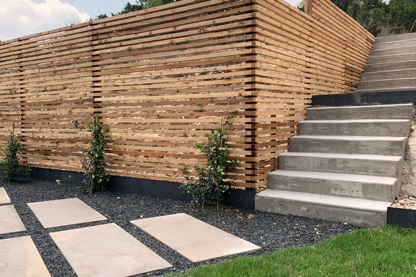 Horizontal slat cedar fence with concrete steps, stepping stones, and gravel beds in a Westlake Hills backyard