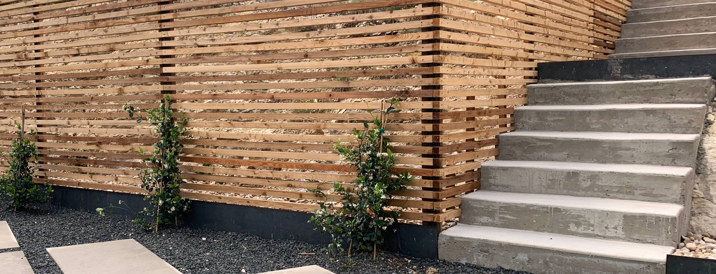 Westlake Hills modern terrace with a horizontal slat fence, concrete steps, stepping stones, and gravel by Thrive Landscape and Design