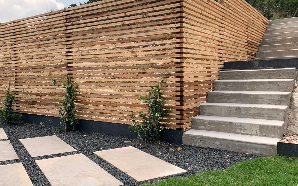 Horizontal slat cedar fence with concrete steps, stepping stones, and gravel beds in a Westlake Hills backyard