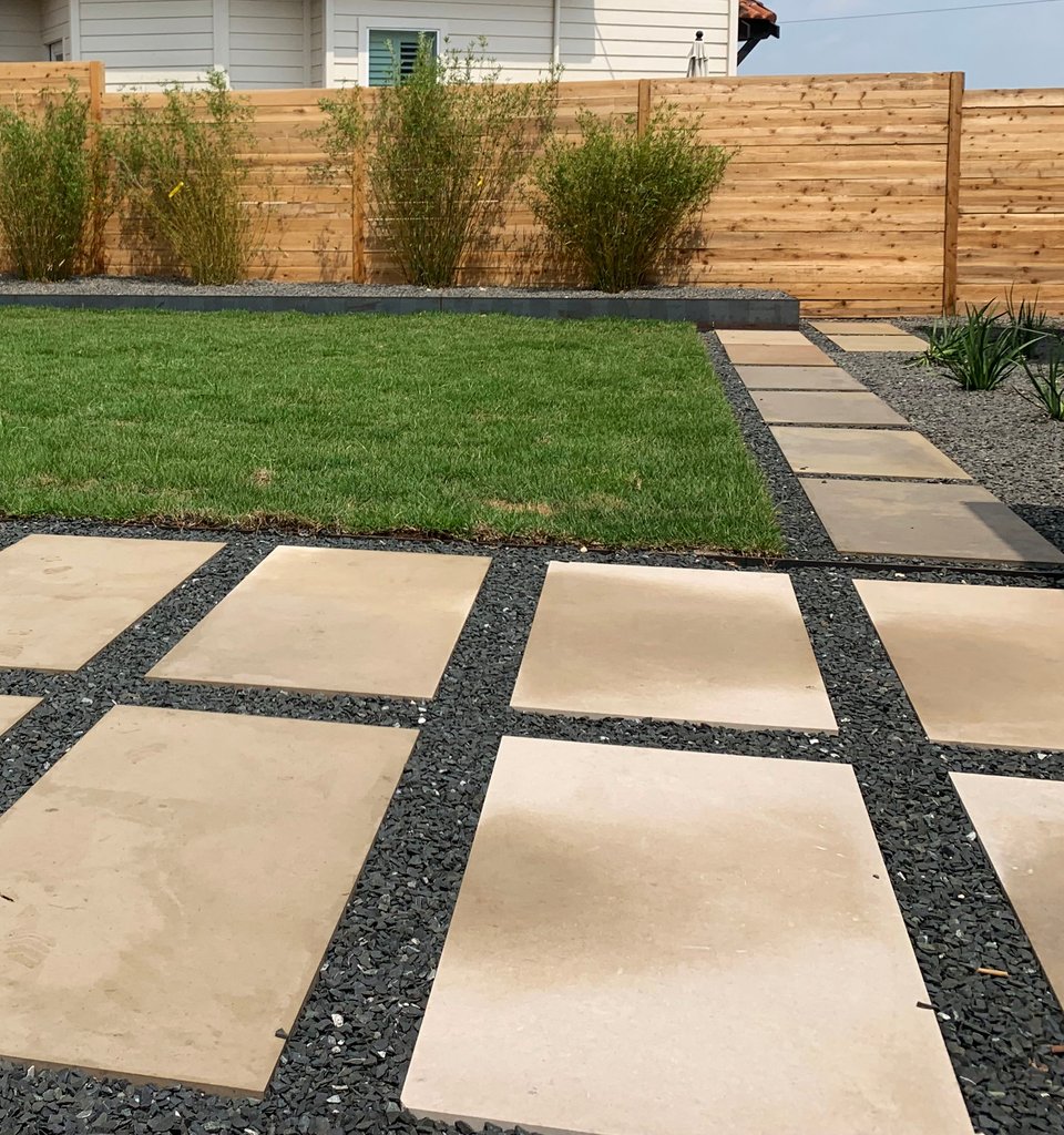 Westlake Hills terrace with new sod, stepping stones, gravel, and a slat fence