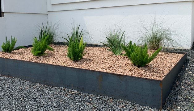 Steel-edged planter bed with gravel and ornamental plants at a Westlake Hills home