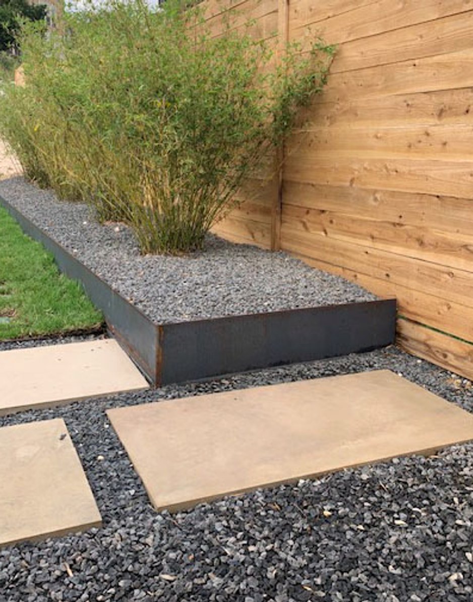 Steel-edged planter with stepping stones, gravel, and bamboo