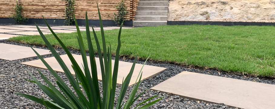 Re-graded Westlake Hills yard with sod, gravel, concrete steps, and stepping stones shaping the slope so water sheds away from the house